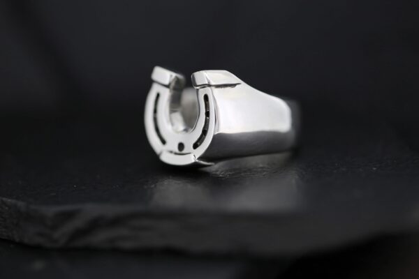 A silver ring featuring a horseshoe design on a black background.