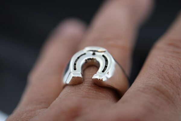 Close-up of a silver horseshoe ring on a finger.