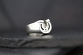 Close-up of a silver horseshoe ring on a dark surface.