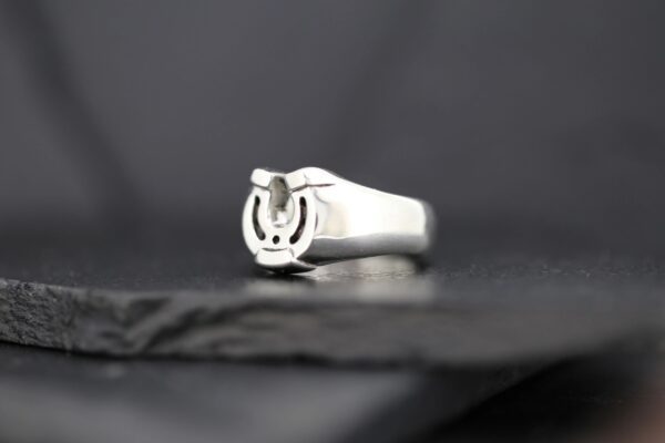 Silver ring with a horseshoe design on a dark background.