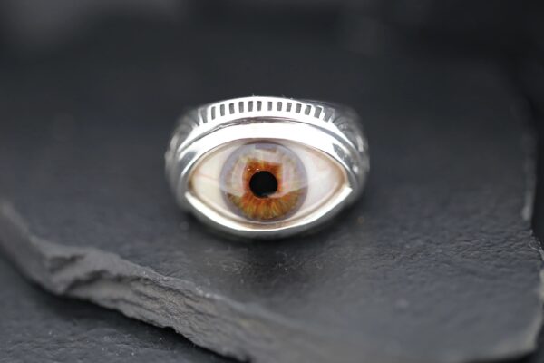 A silver ring featuring a detailed, realistic eye design.