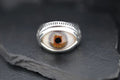 A silver ring featuring a detailed, realistic eye design.