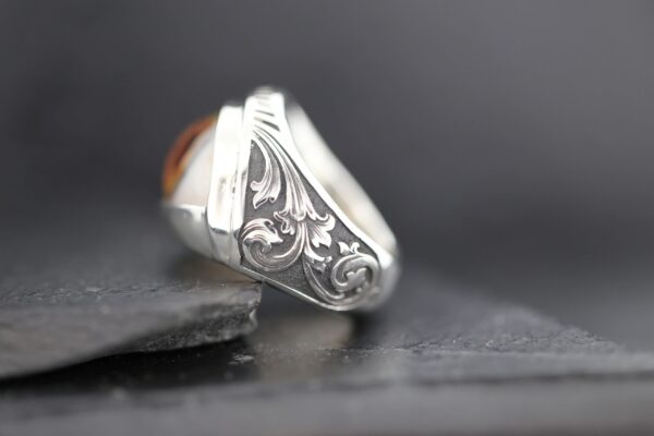 Close-up of an ornate silver ring with intricate floral designs.