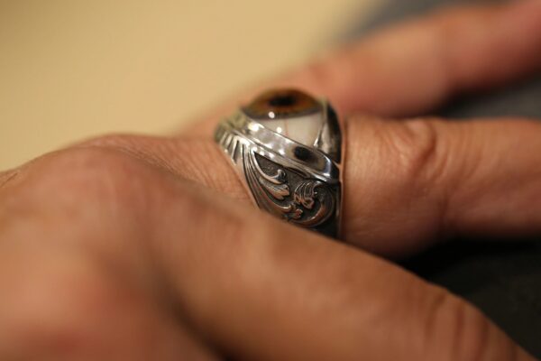 Close-up of a hand wearing a detailed silver ring with an intricate design.