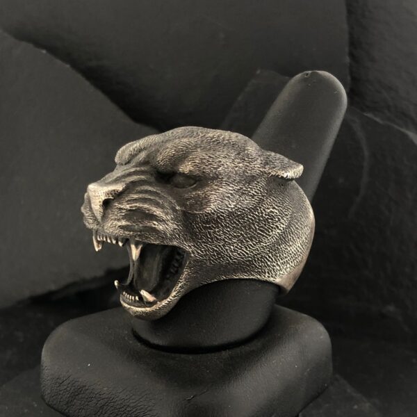 A sculpted panther head with mouth open on a black stand.