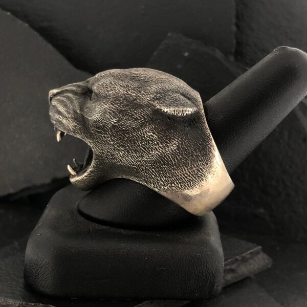 A fierce panther head ring in silver tone on a display stand.