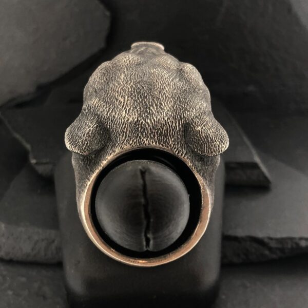 A close-up of a textured ring with a large black stone and claw-like details.