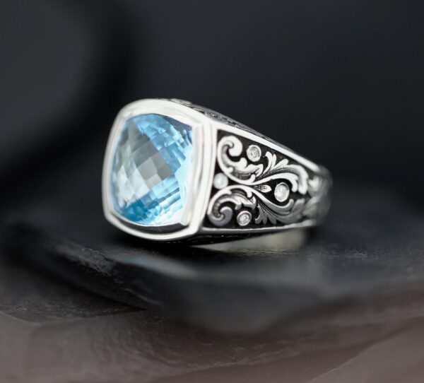 Silver ring with intricate design and blue gemstone.