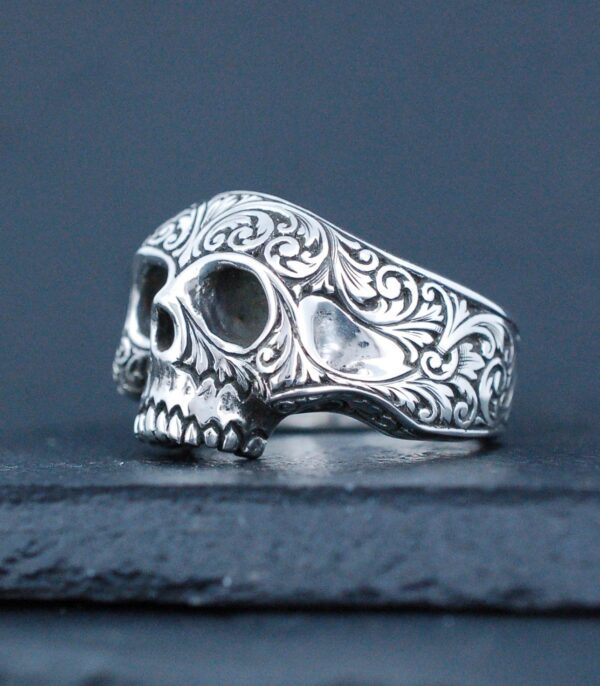 Intricately designed silver skull ring with ornate patterns.