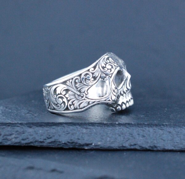 Intricately designed silver skull ring with floral patterns.