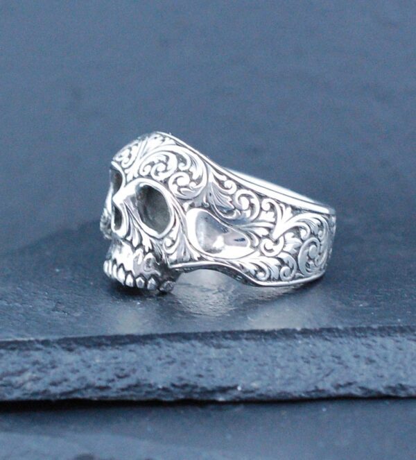 Intricately designed silver skull ring with floral patterns.