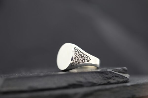 Close-up of an intricately designed silver ring with a triangular pattern.