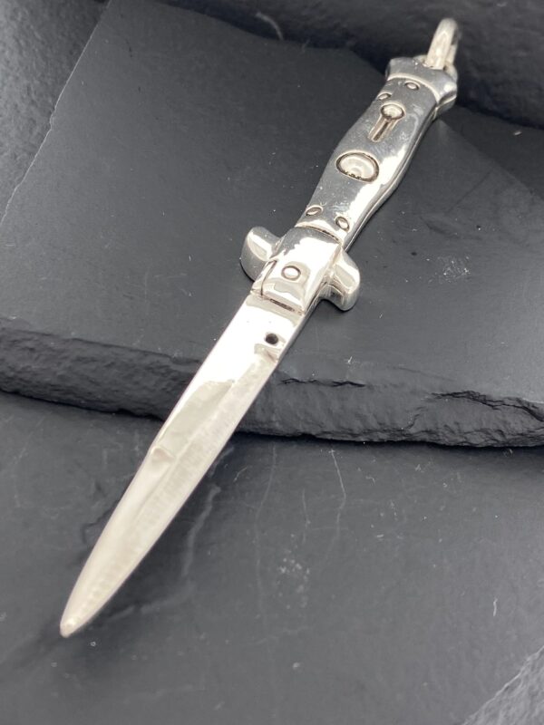 A vintage switchblade knife with a black handle and silver accents.