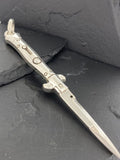 A detailed metal dagger with ornate designs on a dark surface.