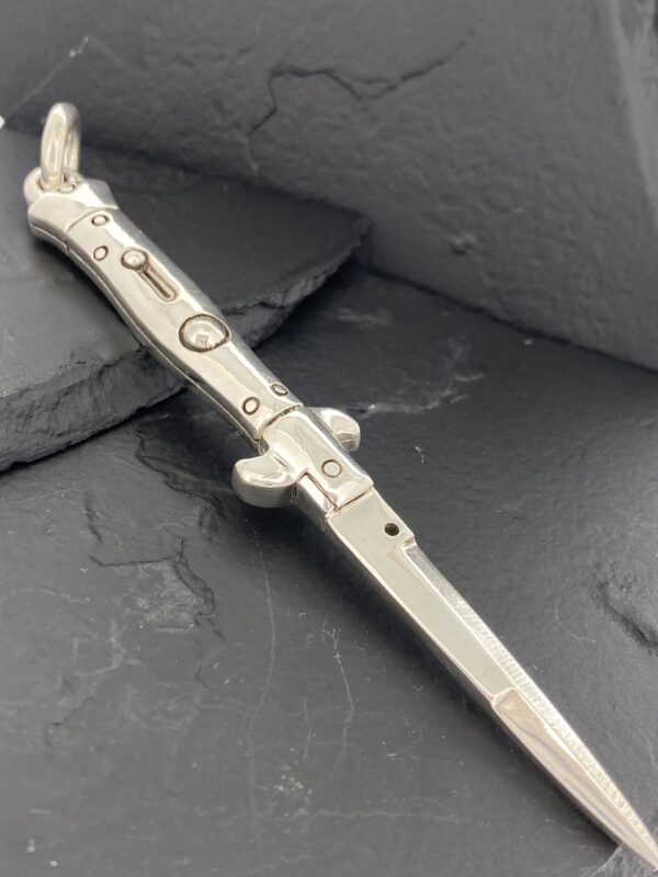 A detailed metal dagger with ornate designs on a dark surface.
