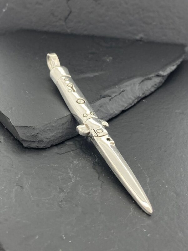 A silver decorative pen with intricate designs on a dark surface.