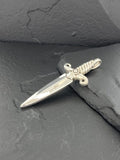 A small dagger-shaped pendant with a twisted handle on a dark surface.