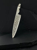 A silver knife-shaped pendant with intricate floral engravings.
