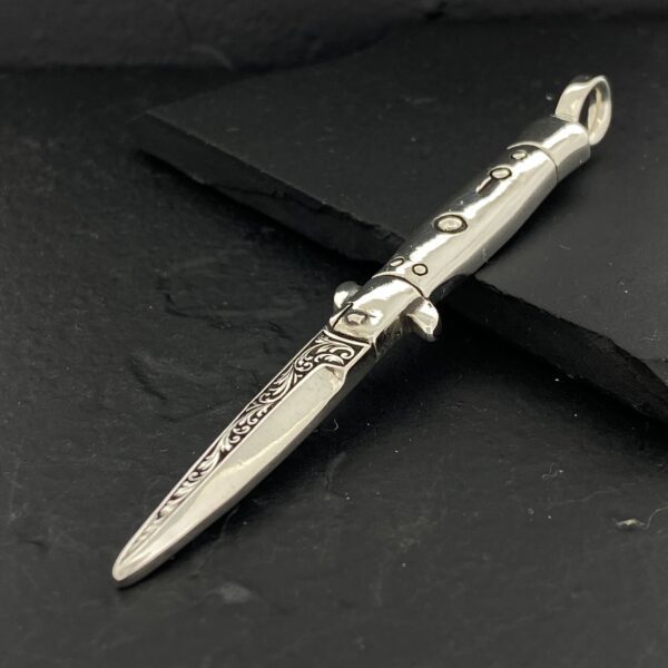 Ornate silver dagger with intricate designs on a dark background.