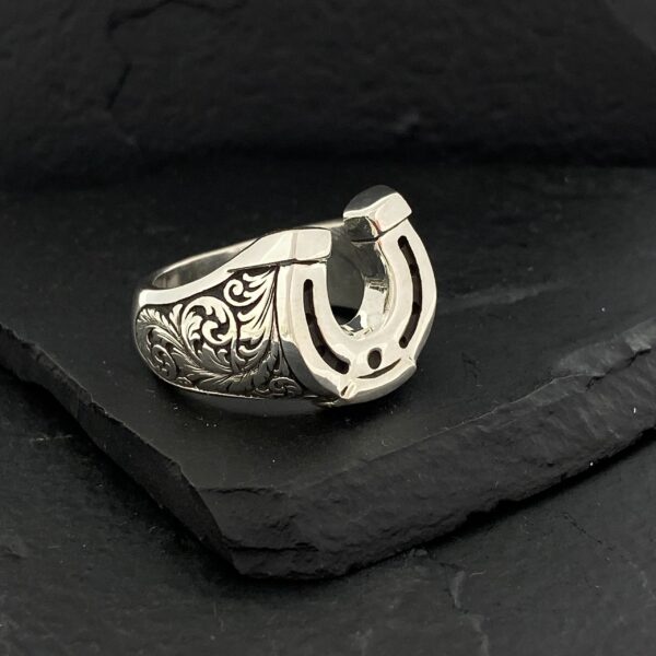 Intricately designed silver ring with a horseshoe motif.