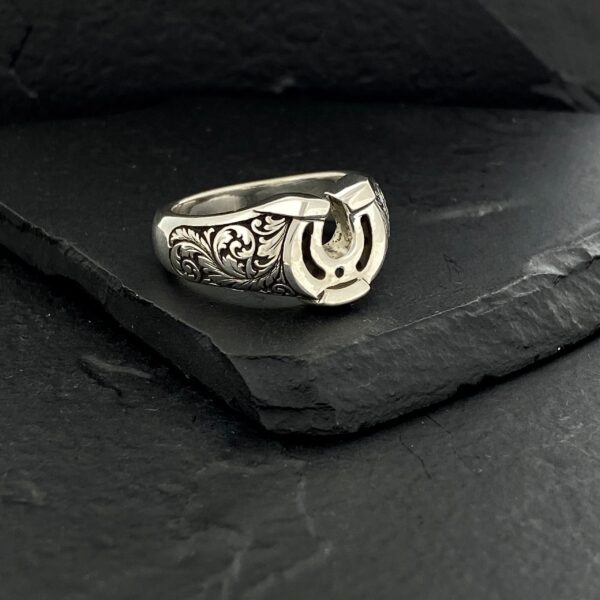 Silver ring with Arabic calligraphy on dark stone background.