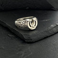 Silver ring with Arabic calligraphy on dark stone background.