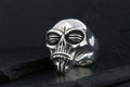A metallic skull ring with intricate details on a dark background.