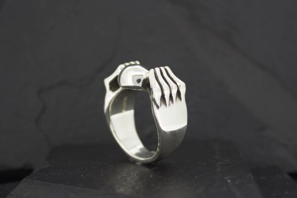 A silver ring designed like a hand gripping.