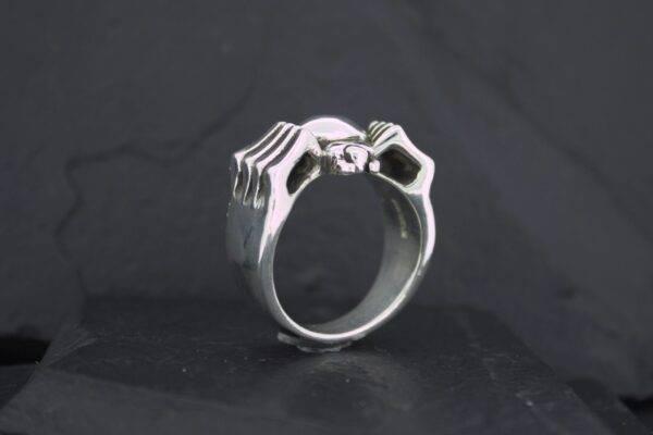 Silver ring shaped like two hands forming a heart.