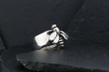 Silver ring shaped like a clenched fist on dark surface.