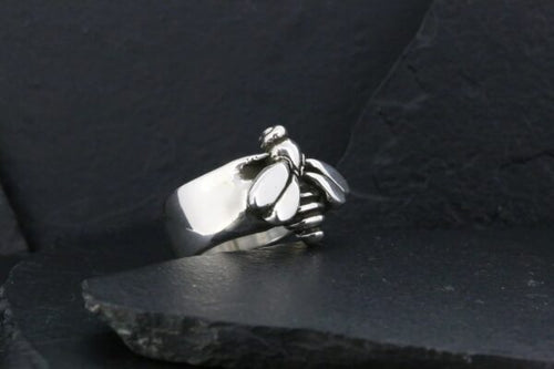 Silver ring shaped like a clenched fist on dark surface.