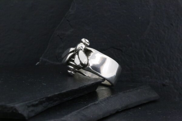Silver ring with a unique claw-like design on a dark surface.
