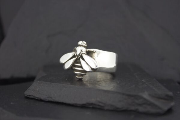 Silver bee-themed ring on a dark surface.