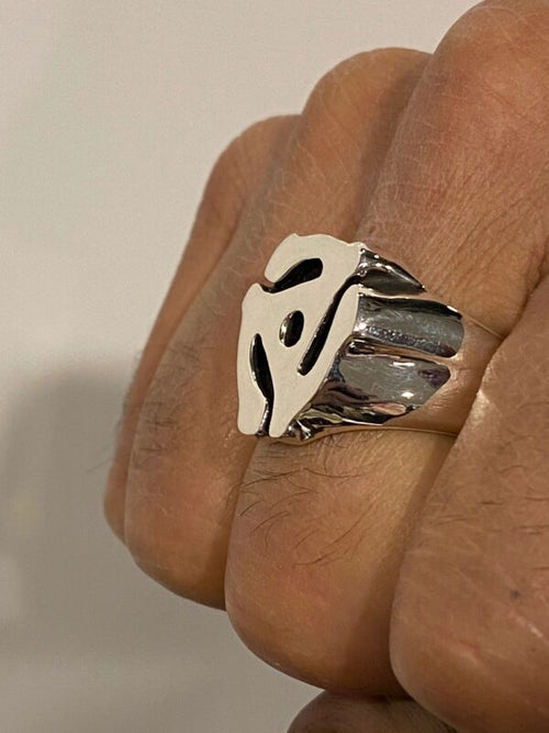 Close-up of a hand wearing a silver ring with a unique abstract design.