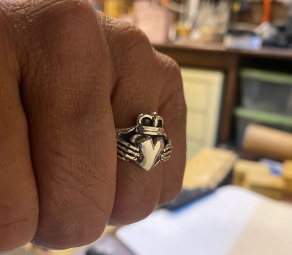 A hand wearing a silver bee-shaped ring.