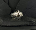 Silver ring with a heart and Om symbol on a dark stone background.