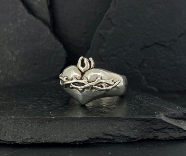 Silver ring with an intricate snake design against a dark background.