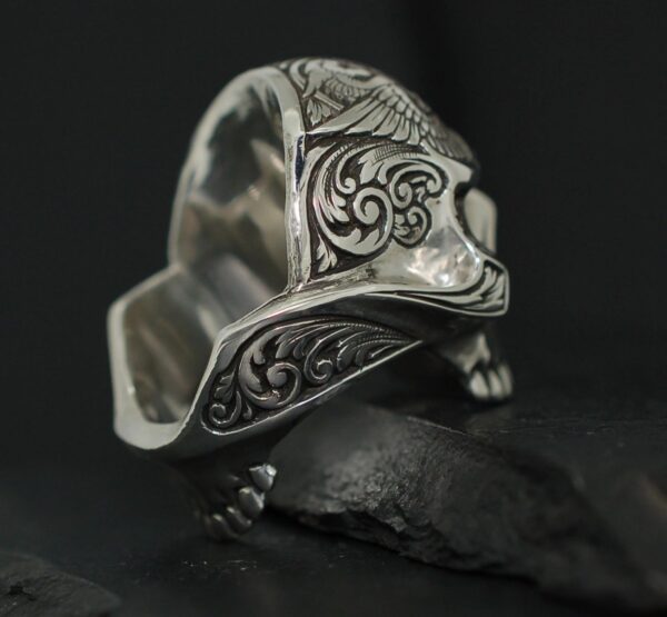 Intricately designed silver ring with ornate patterns on a dark stone.