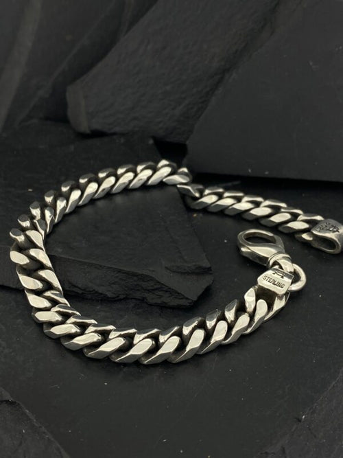 Sleek silver chain bracelet on black background.