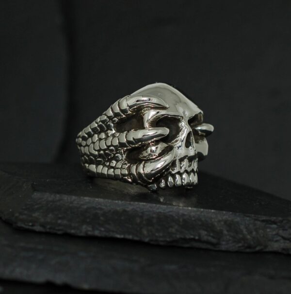 Intricately designed skull ring with claw details on a dark background.