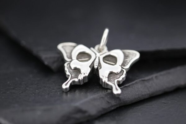 Close-up of a silver butterfly pendant with intricate design.