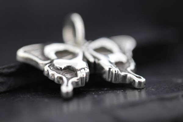 Close-up of a silver key pendant on a chain.