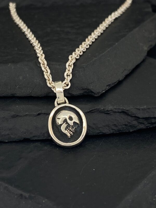 Silver pendant necklace with a skull and crossbones design.
