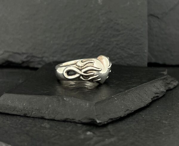 Close-up of a silver ring with an intricate flame design.