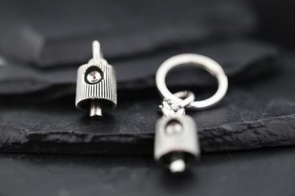 Close-up of a silver keychain with a small pendant on a dark surface.