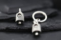 Close-up of a silver keychain with a small pendant on a dark surface.