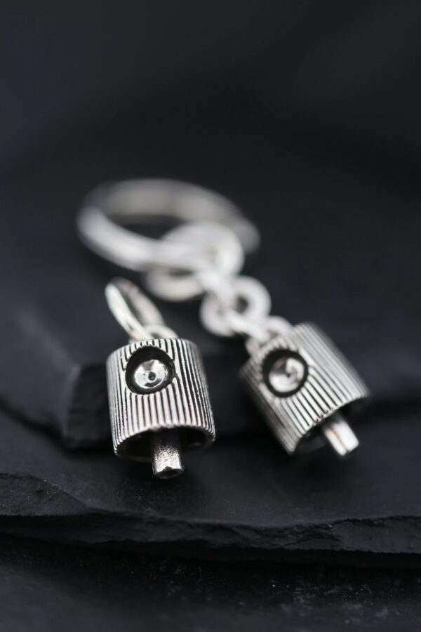 Close-up of silver keychain with two small padlock charms on black fabric.