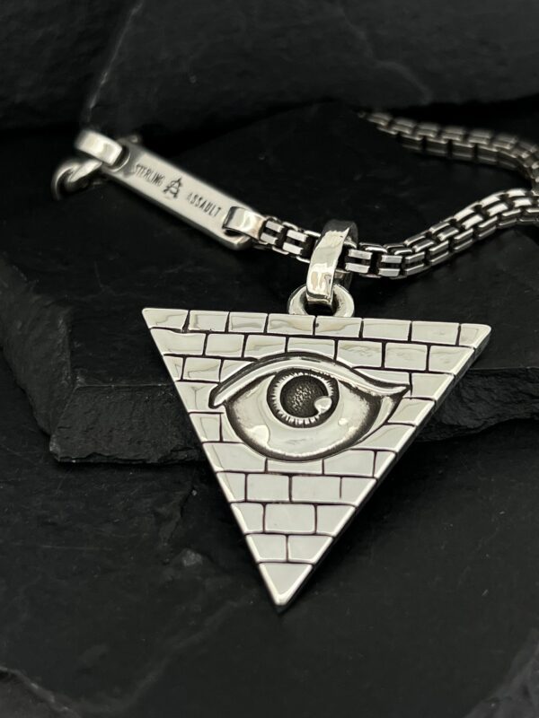 Triangle pendant with an eye and brick pattern on a silver chain.