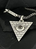 Triangle pendant with an eye and brick pattern on a silver chain.