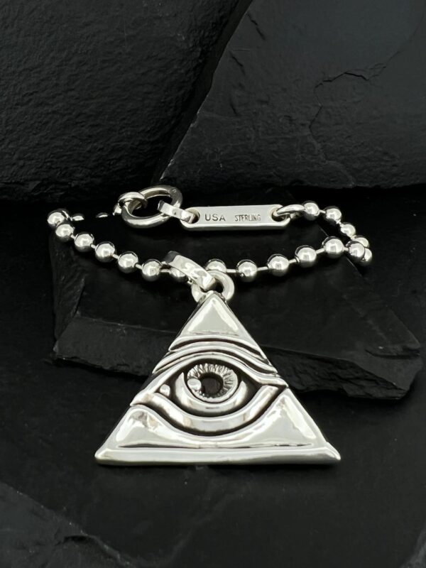 Silver pendant shaped like an eye within a triangle on a beaded chain.